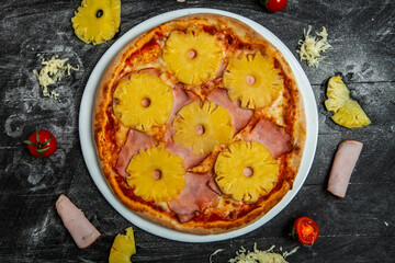 Pizza with pineapple and mozzarella on black wood background.