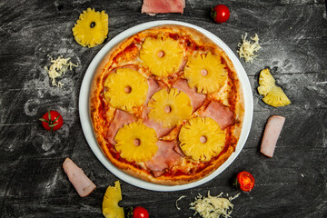 Pizza with pineapple and mozzarella on black wood background.