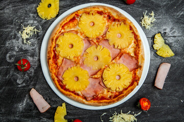 Pizza with pineapple and mozzarella on black wood background.