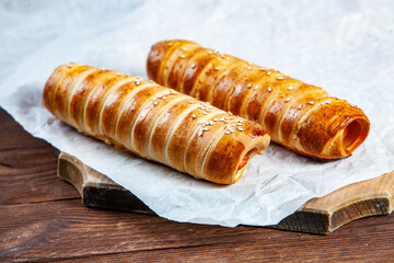 Fresh tasty sausage rolls on plate. fresh sausage in dough on wood background.