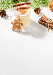 Fototapeta na wymiar Christmas typical desserts eggnog with cinnamon, ginger man on white wooden table. Vertical shot.