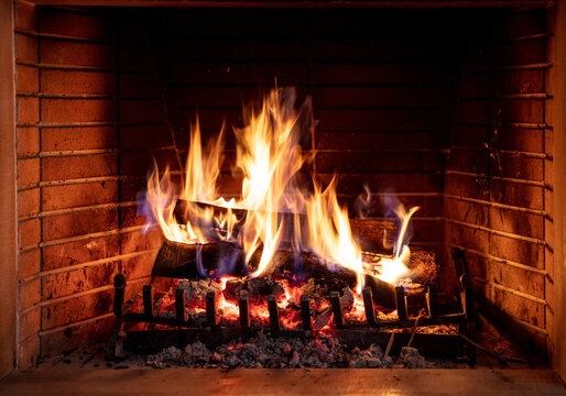 Christmas time, cozy fireplace. Wood logs burning, fire bricks background, relaxation and warm home