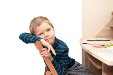 Cute tired preschool boy sitting at the table.Home education concept or development activities.Online learning.Isolated on white.