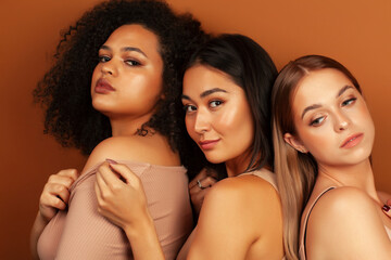 Obraz premium young pretty asian, caucasian, afro woman posing cheerful together on brown background, lifestyle diverse nationality people concept