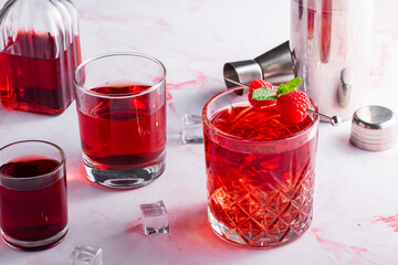 red cocktail with raspberries on a pink background