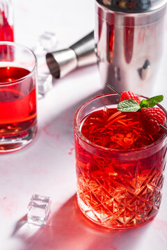 red cocktail with raspberries on a pink background