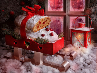 Christmas Stollen. Traditional Sweet Fruit bread with powdered sugar. Christmas gift rides a sled in the snow - 469973790