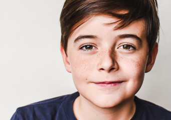 Close up portrait of cute young boy with brown hair and freckles.