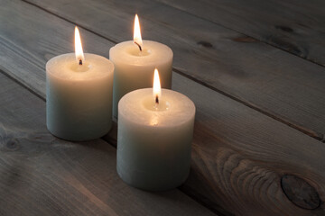 Fototapeta na wymiar Three candles on old wooden background