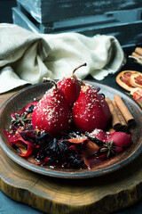 Spicy pears in wine sauce with nuts on a brown bowl. Blurred background, shallow depth of field