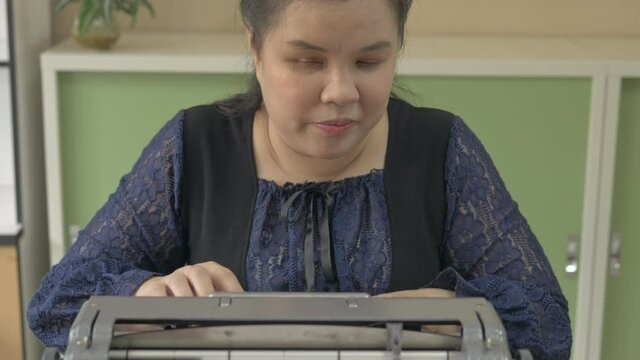 Disabled blind person woman using vintage braille typewriter a simple machine used to write Braille character encoding for visual impairment people.