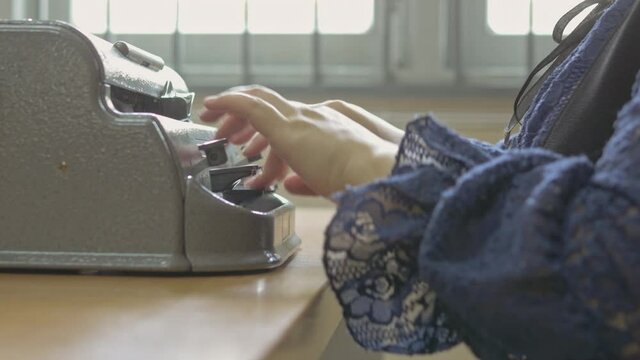 Close-up handheld shot of disabled blind person woman hands using vintage braille typewriter a simple machine used to write Braille character encoding for visual impairment people.