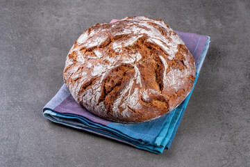 Traditional wholemeal rye bread in country style. Single object on a checkered napkin. Top view, copy space