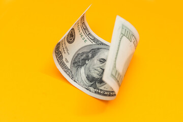 One hundred dollar bills closeup on yellow background