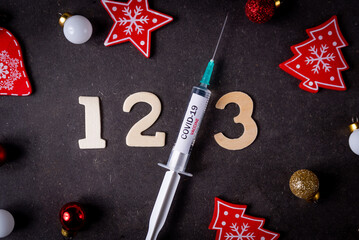 Third covid vaccine dose and jab concept and numbers and Christmas decorations. Syringe is seen on table as a concept for the 3rd covid-19 vaccine dose, also called booster shot - obrazy, fototapety, plakaty