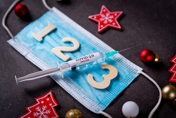 Third covid vaccine dose and jab concept with face mask and numbers and Christmas decorations....