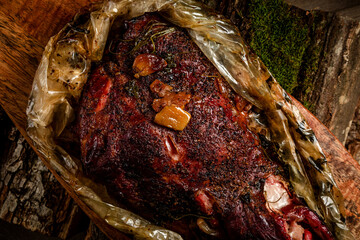 smoked meat. beef leg cooked in a smokehouse on woody background