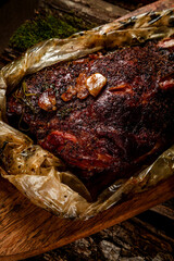 smoked meat. beef leg cooked in a smokehouse on woody background
