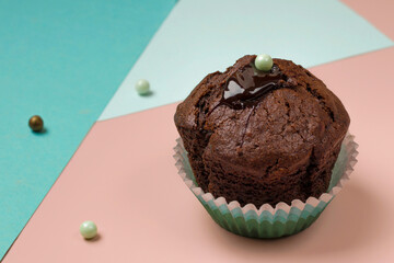 Geometric trend. Close-up of delicious chocolate muffin on pink and blue background. Creative minimalist food design. Holiday concept. Copy space.