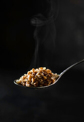 spoon with boiled buckwheat on a dark background