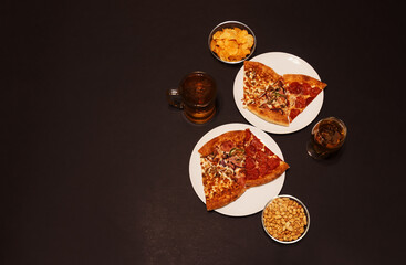 Slices of pepperoni pizza, ham pizza and chicken pizza, glass of beer, mug of beer, peanuts and potato chips. Top view.