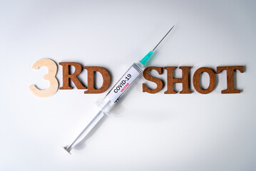 Third covid vaccine dose and jab concept with face mask. Syringe is seen on table as a concept for...