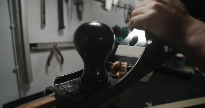 Luthier uses hand plane for wood processing at his workshop. Guitar maker uses jack plane in slow motion, 4k 60p Prores HQ
