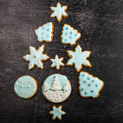 Christmas tree made of Christmas gingerbread decorated with blue and white icing on a black wooden background. Square.