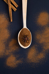 Top view of cinnamon in the wooden spoon on the black background. Location vertical.