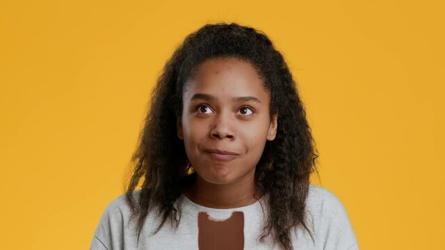 Happy African American Teenager Girl Eating Chocolate Over Yellow Background