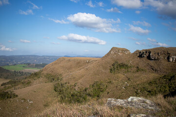 top of the mountain in a day of blue sky, white clouds and green vegetation around