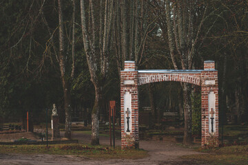 An old cemetery gate with brick pillars giving a moody or scary feeling. Balozu kapi, Jelgava,...