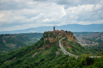 Fototapeta na wymiar Tuscany, Italy 2019, the old town of Civita on the top of a mountain, a bridge goes to it, against the background of mountains