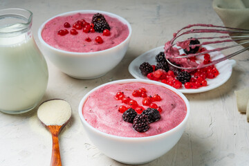 Mousse pudding made from semolina and red currant berries. White table, two bowls with mousse.