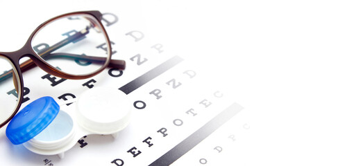 Contact lenses case and eye glasses on and eye test chart. Vision concept. Way to improve vision