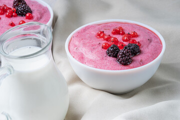 Dessert from semolina with red currant berries in a white glass on a cloth background.