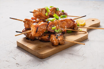Chicken fillet yakitori on a white table. Appetizing slices of fried chicken on skewers.