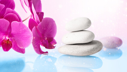 Wellness, relax, massage and wellbeing concept. Spa stones and orchid flower over light pink and blue background