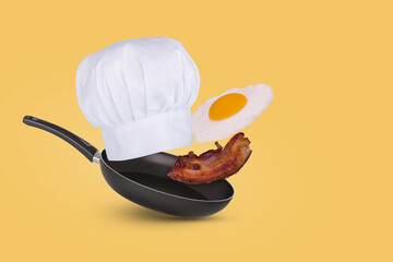 Minimal idea with a frying pan, chef hat, flying fried egg and bacon on a yellow background.