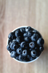Cup of fresh blueberries on wooden table. Flat lay.