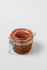 Homemade organic sauce made from dried tomatoes, olive oil and spices in a glass jar on  white background, place for text, isolate