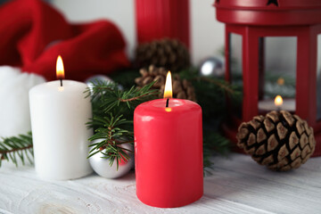 Burning candles and festive decor on white wooden table. Christmas eve
