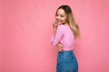 Young beautiful woman. Trendy woman in fashionable pink crop top. Positive female shows facial emotions. Funny model isolated on pink background with free space