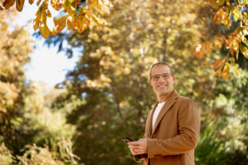 Fototapeta premium man with jacket and cell phone in hand outdoors smiling looking to the side mature couple taking a selfie on location