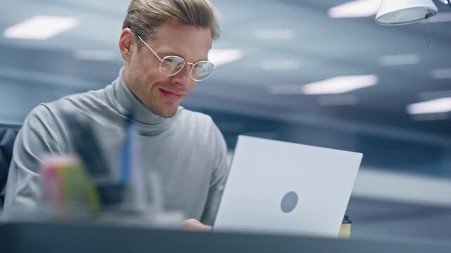 360 Degree Office: Handsome Businessman Sitting at Desk Using Laptop Computer. Digital Entrepreneur working with Big Data Digital e-Commerce Project Statistics. Tracking Shot. Camera Moving Around