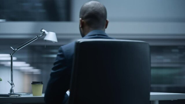 360 Degree Office: Handsome Successful Black Businessman Sitting at Desk Using Laptop Computer. African American Entrepreneur in Suit working with Stock Market Investing. Moving Around Tracking Shot