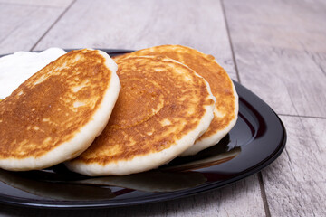 Pancakes and sour cream on plate on wooden table