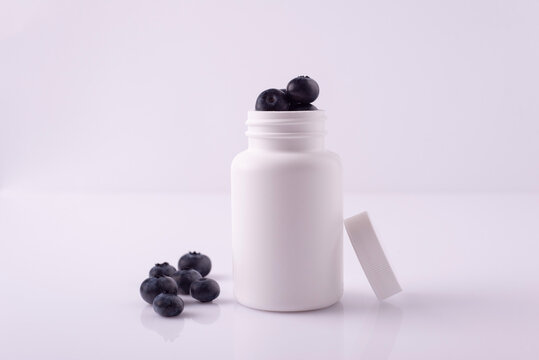 blueberry pills in white bottle on white background