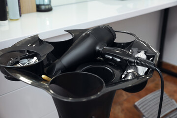 Modern hair dryer and clips on stand in beauty salon