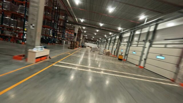 Flight in warehouse. FPV copter view inside huge contemporary industrial building storage of logistic center. Product distribution. Delivery. Logistics.